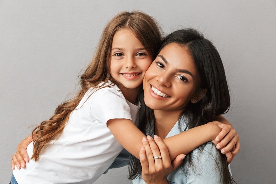 Mother and daughter smiling on grey background